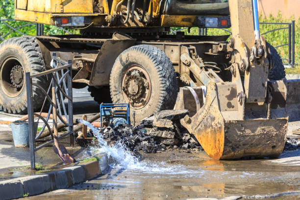 Excavator helps to eliminate the problem of breaking a pipe in the street on a hot summer day stock photo