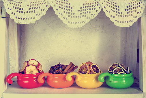 assortment of dried fruits, spices and spices in colored cups close-up on white wooden background, healthy food, retro style