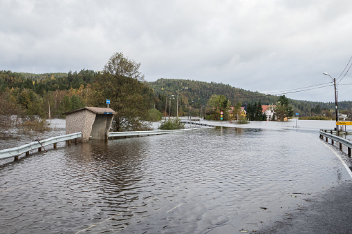 Water flooding the road - October 3, 2017: Flooding from the river Tovdalselva in Kristiansand, Norway. Water fills the road and the bus stop at Drangsholt.