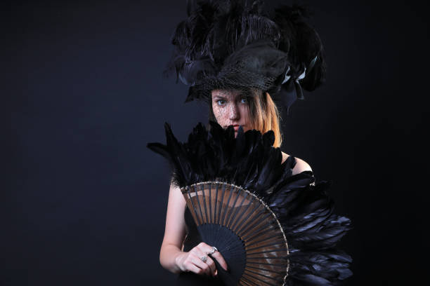 istock Young woman with a black feather fan and hat 862442058