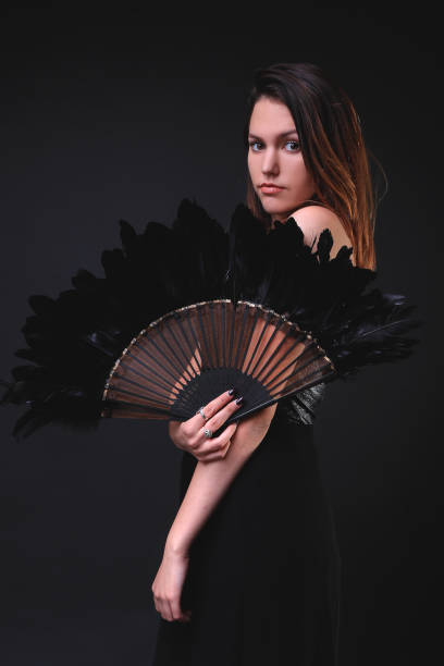 istock Young woman with a black feather fan and hat 862443068