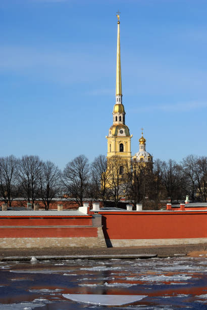 la flèche de la cathédrale principale contre le ciel bleu et les murs de la forteresse de petropavlovskaya sur les rives de la neva, un jour de printemps lumineux à saint-pétersbourg. - surrounding wall sky river dome photos et images de collection