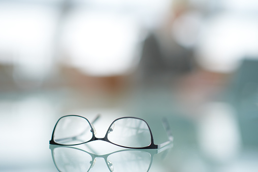 Close-up of female eyeglasses placed and reflected on glassy surface, business audit concept