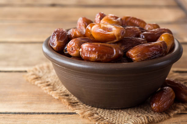 istock Dried dates fruit in ceramic bowl on wooden table. 862461656