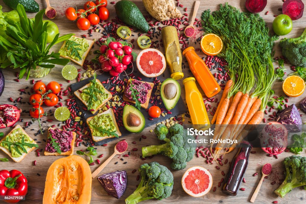 Comida vegana saludable. Bocadillos y verduras sobre fondo de madera. Dieta de desintoxicación. Diferentes coloridos zumos recién exprimidos. vista superior - Foto de stock de Comida vegana libre de derechos