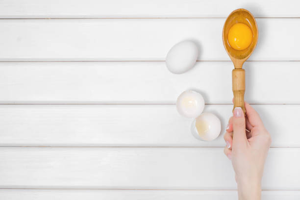 istock Eggs wooden spoon yolk female hand 862480306