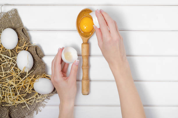istock Eggs wooden spoon yolk female hand 862480352