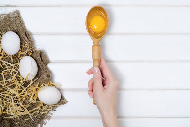 istock Eggs wooden spoon yolk female hand 862480562