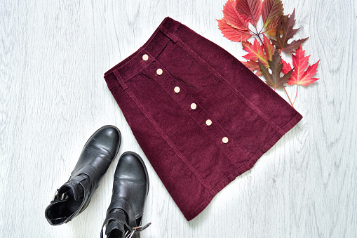 Falda de ante Burdeos, botas negras y hojas rojas. Concepto de moda. photo