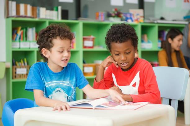 istock Row of multiethnic elementary students reading book in classroom. Vintage effect style pictures. 862508742