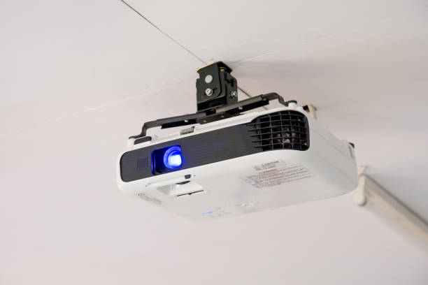 istock White projector hanging on the ceiling of conference room. 862518004