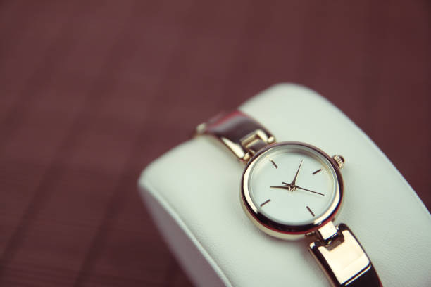 gold women's wrist watch with diamonds, a chronograph, a metal bracelet on a light background close-up. Gift for women for the holiday, time management concept. High quality photo