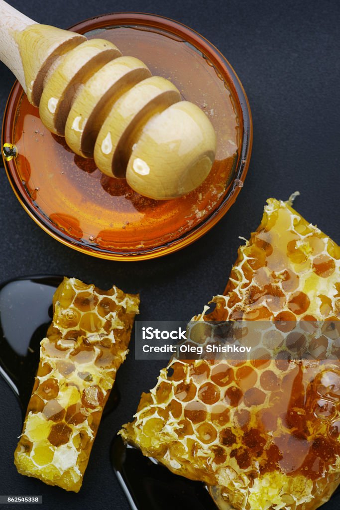 Honeycombs on a black background top view, honey bee flows out of honeycomb on a black background, wooden spoon for honey Beehive Stock Photo