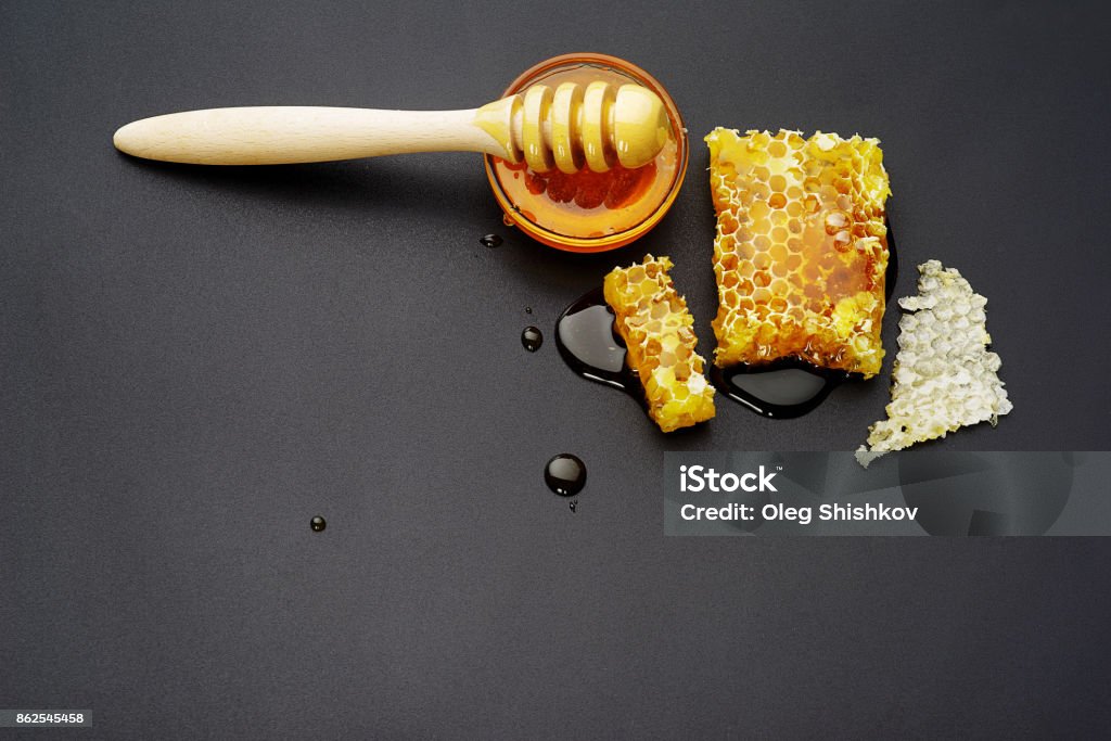 Honeycombs on a black background top view, honey bee flows out of honeycomb on a black background, wooden spoon for honey Beehive Stock Photo