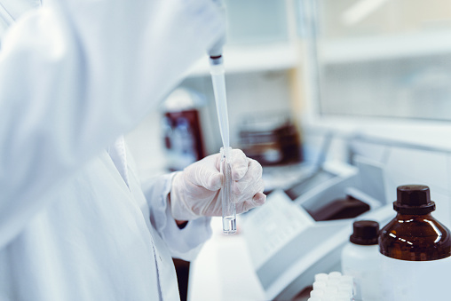 A chemist wearing protective gloves conducting a scientific experiment in a laboratory