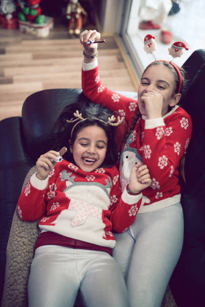 istock Two Smiling Little Sisters Lying on Sofa and Eating Chocolate 862549402