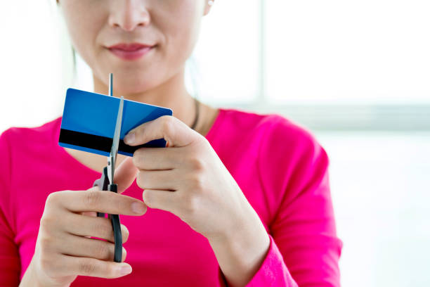 mulher cortando um cartão de crédito - cutting currency scissors home finances - fotografias e filmes do acervo