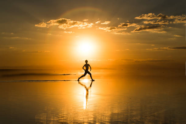 Woman looks at the sun set after sports training. She is holding a water bottle and she is wearing a GPS/pulse watch.
