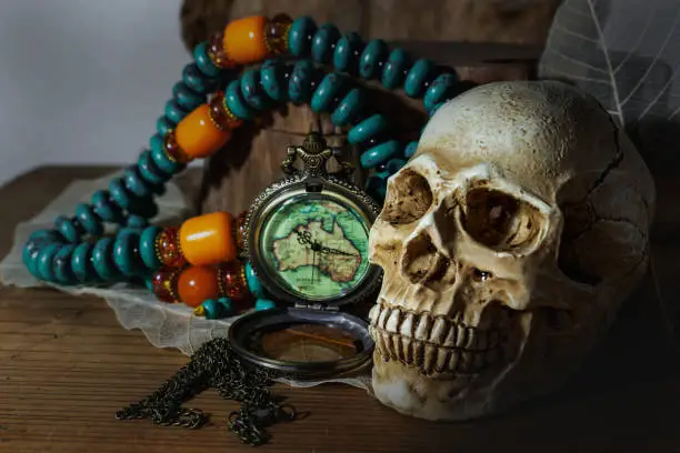 Photo of Still life photography pocket watch , bead necklace and human skulls in dark vintage tone