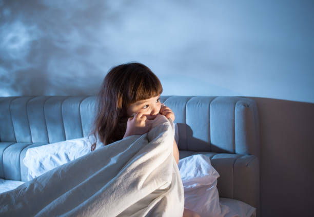 la chica oculta su rostro con una manta en la cama por la noche - child bedtime imagination dark fotografías e imágenes de stock