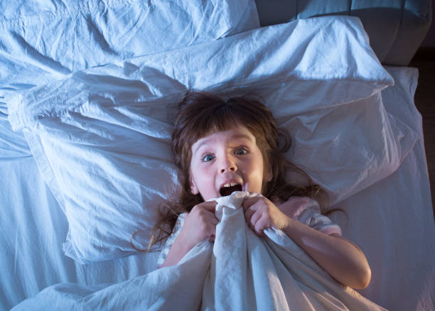 女の子はベッドで横になっている恐怖 - child bedtime imagination dark ストックフォトと画像