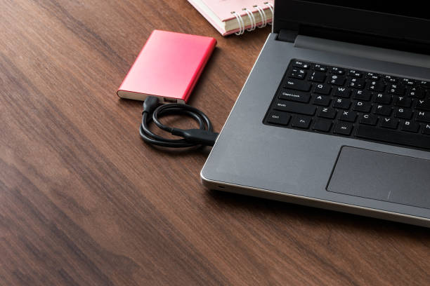 istock external hard drive (HDD) connected to laptop for transfer or backup data on wooden desktop 862575622