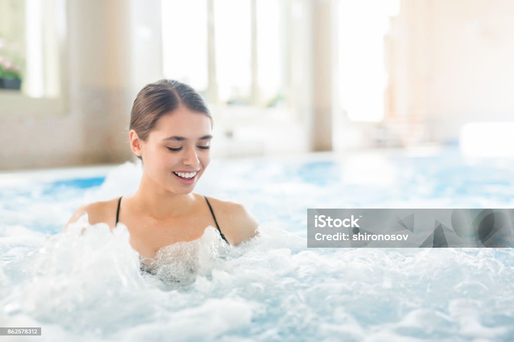 Delicate waves Young woman enjoying warm gentle water waves in whirlpool Adult Stock Photo