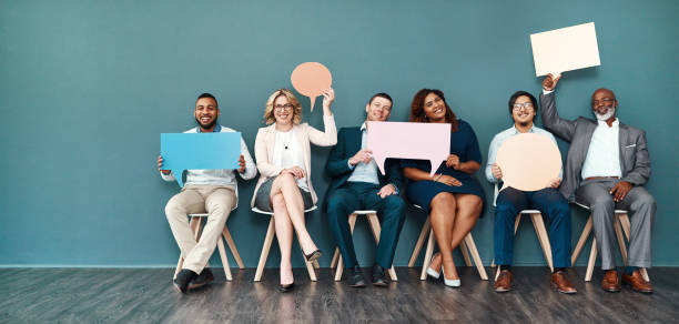 Let’s start a conversation Shot portrait of a diverse group of businesspeople holding up speech bubbles while they wait in line interview event photos stock pictures, royalty-free photos & images