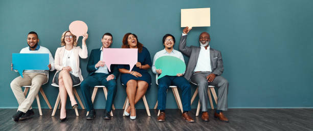 We speak the language of success Shot portrait of a diverse group of businesspeople holding up speech bubbles while they wait in line announce stock pictures, royalty-free photos & images