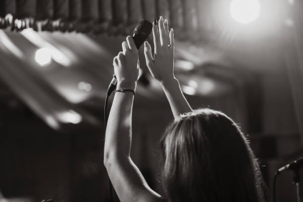 istock Microphone in female hands close-up. Black and white photo. A pub. Bar. A restaurant. Classical music. Evening. Night show. 862601174