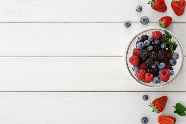 istock Mixed berries in glass bowls on white wooden table top view 862604802