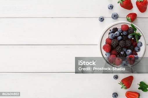 istock Mixed berries in glass bowls on white wooden table top view 862604802