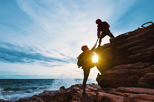 Young asian couple climbing up on the mountain,hiking and team work concept.