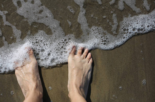 istock feet  on the seashore and wave with foam 862609046