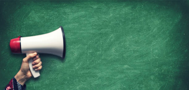 istock hand with megaphone on blank green chalkboard background 862620102