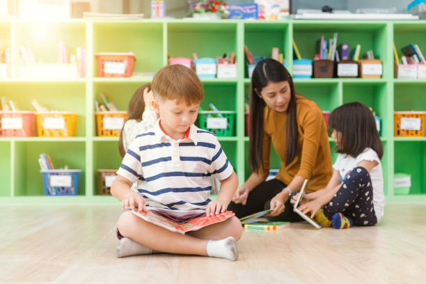 istock Row of multiethnic elementary students reading book in classroom. Vintage effect style pictures. 862622568