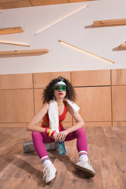 fashionable woman sitting on boombox fashionable woman in bright body suit with towel sitting on boombox 80s aerobics stock pictures, royalty-free photos & images