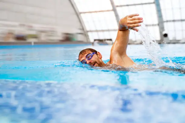 Photo of Man swimming in an indoor swimming pool.