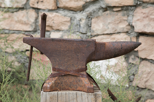 An old, rusty anvil on a wooden post
