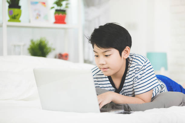 istock Cute asian boy rest on bed and typing laptop computer. 862638928