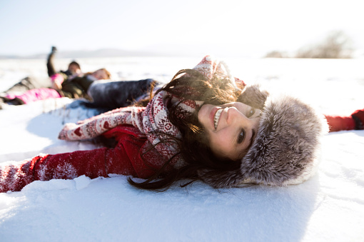 Beautiful young woman with her family, having fun in the snow. Sunny white winter nature.