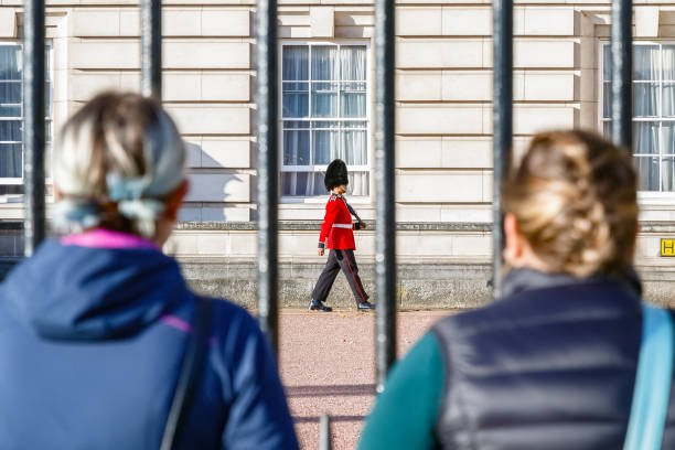dois turistas observando uma sentinela de guardas granadeiros a patrulhar o exterior do palácio de buckingham - changing the guard - fotografias e filmes do acervo