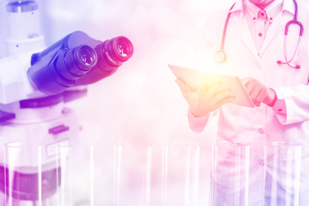 Medical science research and development concept - Doctor holding tablet computer with scientific instrument, microscope and  chemical test tube in lab background.