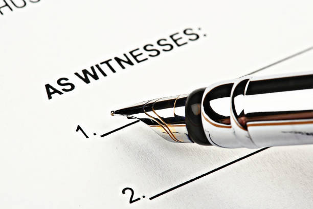 Fountain pen hovering above 'Witness' section of official document A metal fountain pen is held just above the 'Witness' section on a printed form, about to sign. witness signature stock pictures, royalty-free photos & images