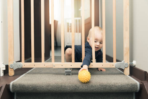 child playing behind safety gates in front of stairs at home child playing behind safety gates in front of stairs at home gate stock pictures, royalty-free photos & images