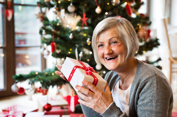 istock Senior woman in front of Christmas tree with present. 862660726