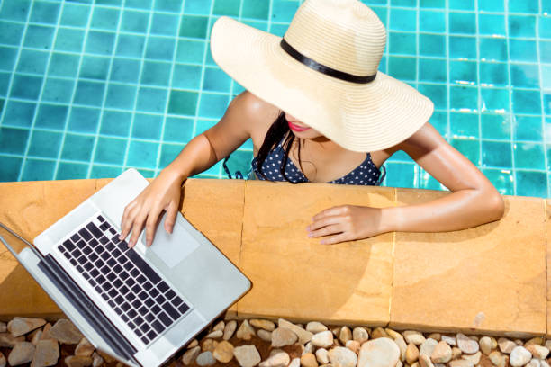 istock Woman bikini using laptop computer blank screen at swimming pool in resort edge 862663990