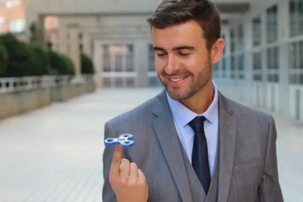 Photo of Cute businessman playing with a hand spinner