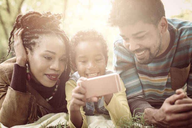 istock African American parents with their daughter in park using mobile phone. 862674886