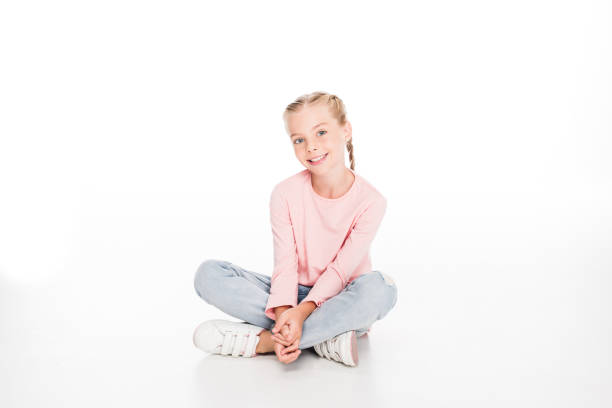 Cheerful child sitting on floor with legs crossed, isolated on white